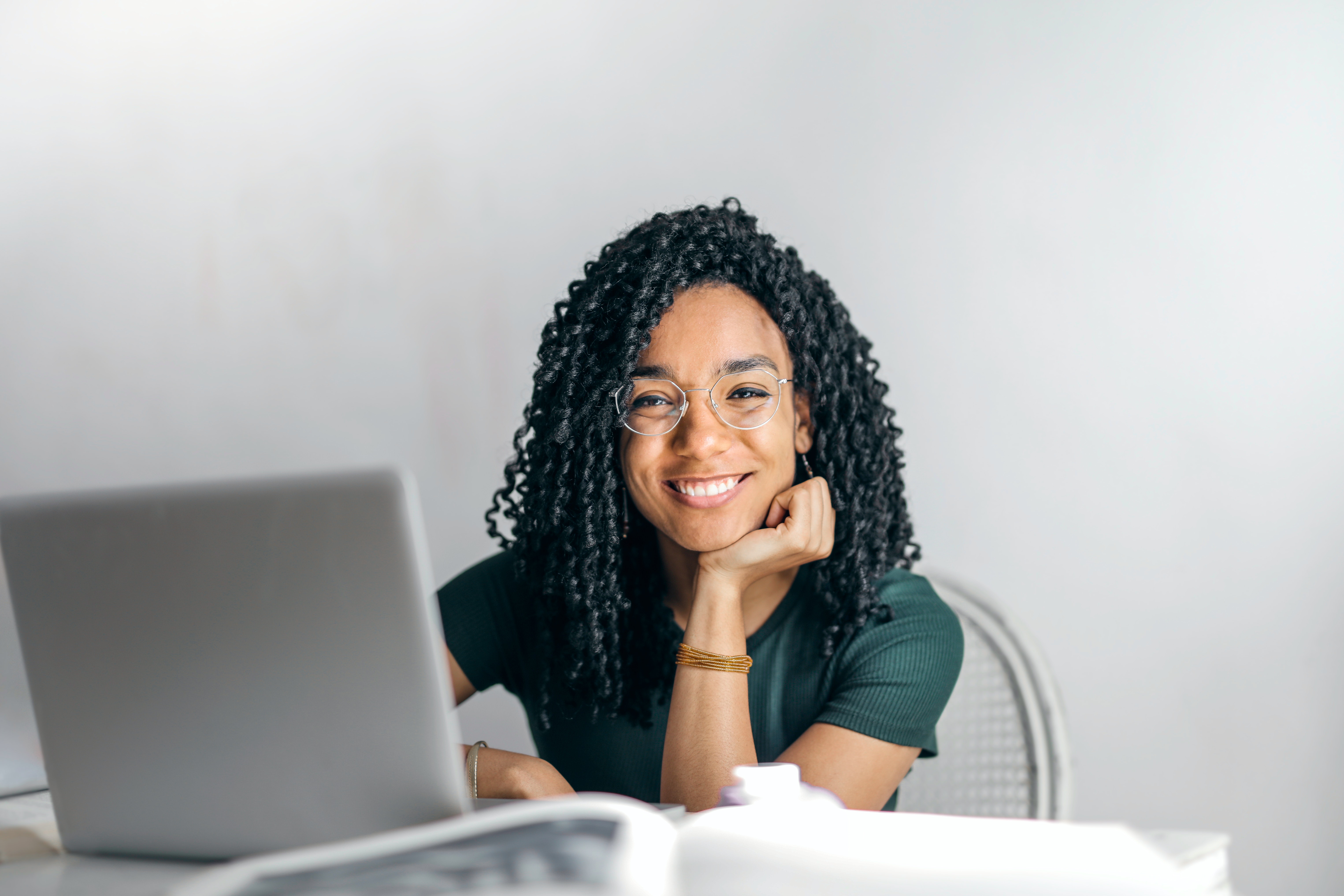 Mujer con gafas sonriendo mientras trabaja frente a una laptop